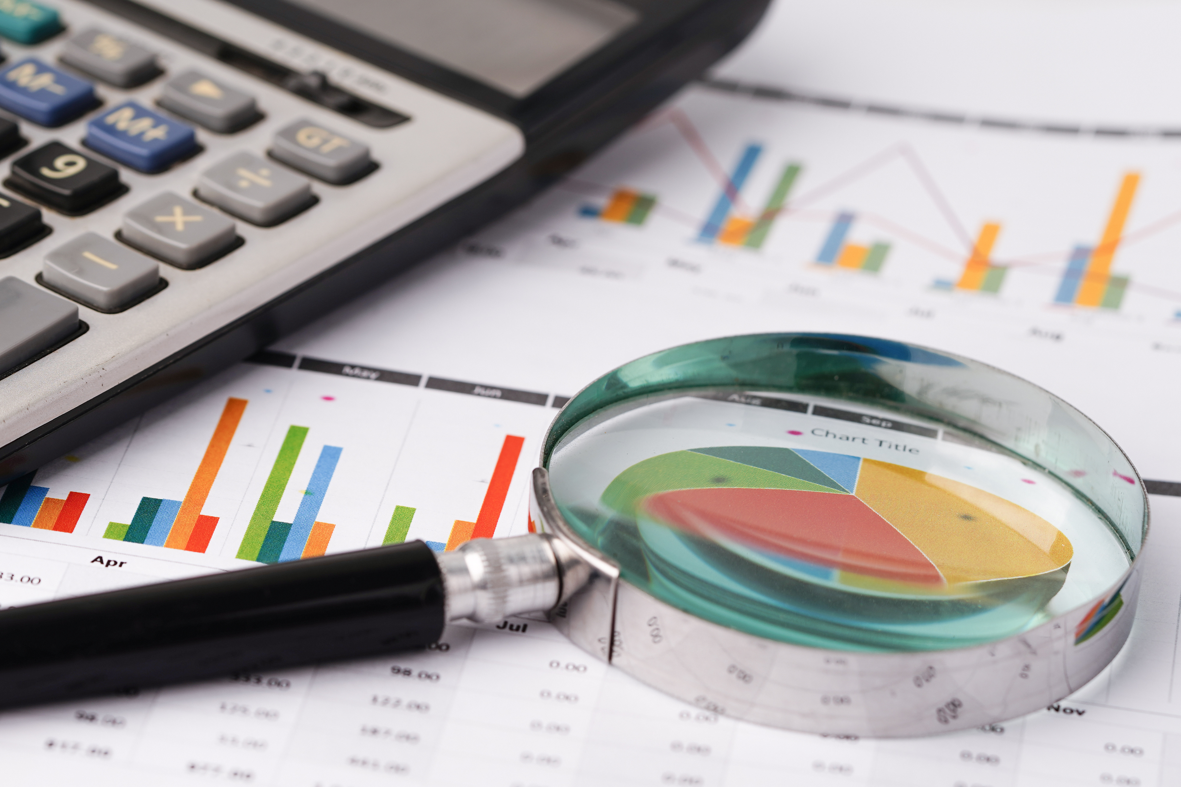 A calculator and magnifying glass on top of a sheet of charts