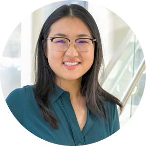 A headshot of Qinglan Ling, wearing glasses and a smile. She is wearing a teal blouse in a pose in front of a large window in the background.